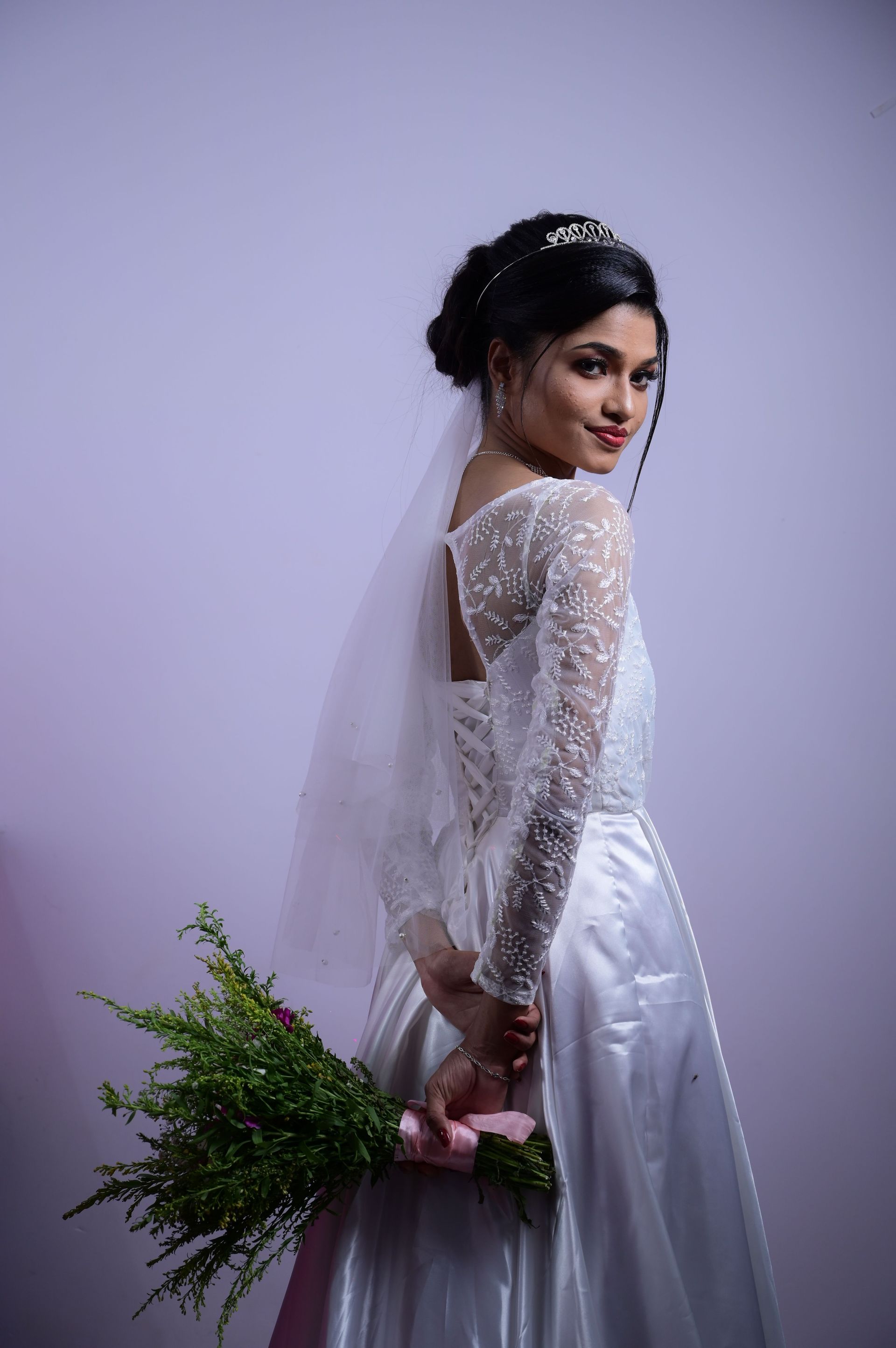 Bride in white wedding dress holding bouquet, showcasing elegance and grace.